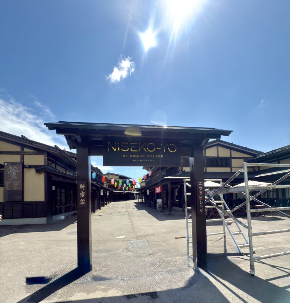 北海道ニセコビレッジの商業エリア「NISEKO-YO」入口ゲート。和モダンな街並みとカラフルな提灯が並ぶメイン通りを望む