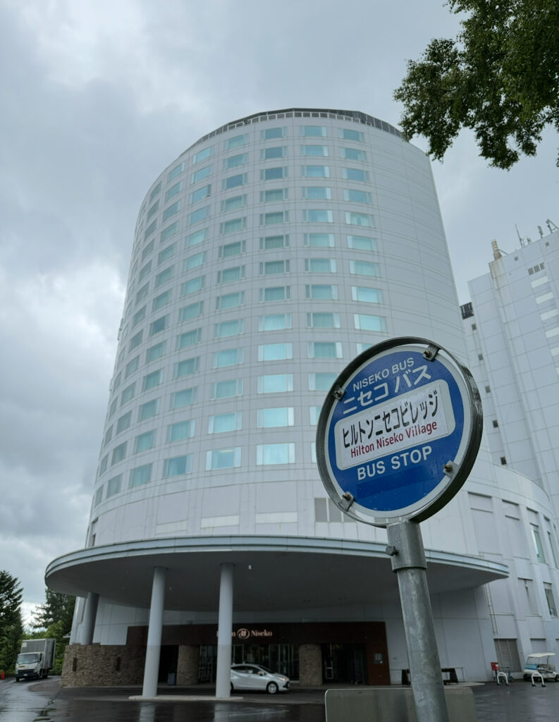 Exterior of Hilton Niseko Village hotel with ski bus stop in front — convenient resort accommodation in Annupuri Niseko Hokkaido near hot springs and ski slopes