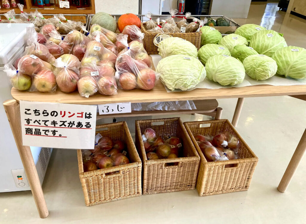 カルデラ温泉の売店で、旬の地元の野菜、キャベツやりんごが並べてある