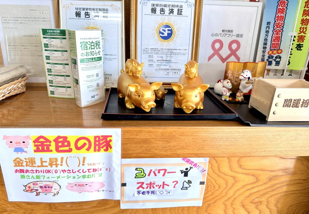 ワイス温泉旅館の受付に飾られた金色の豚の置物と心のバリアフリー認定表示