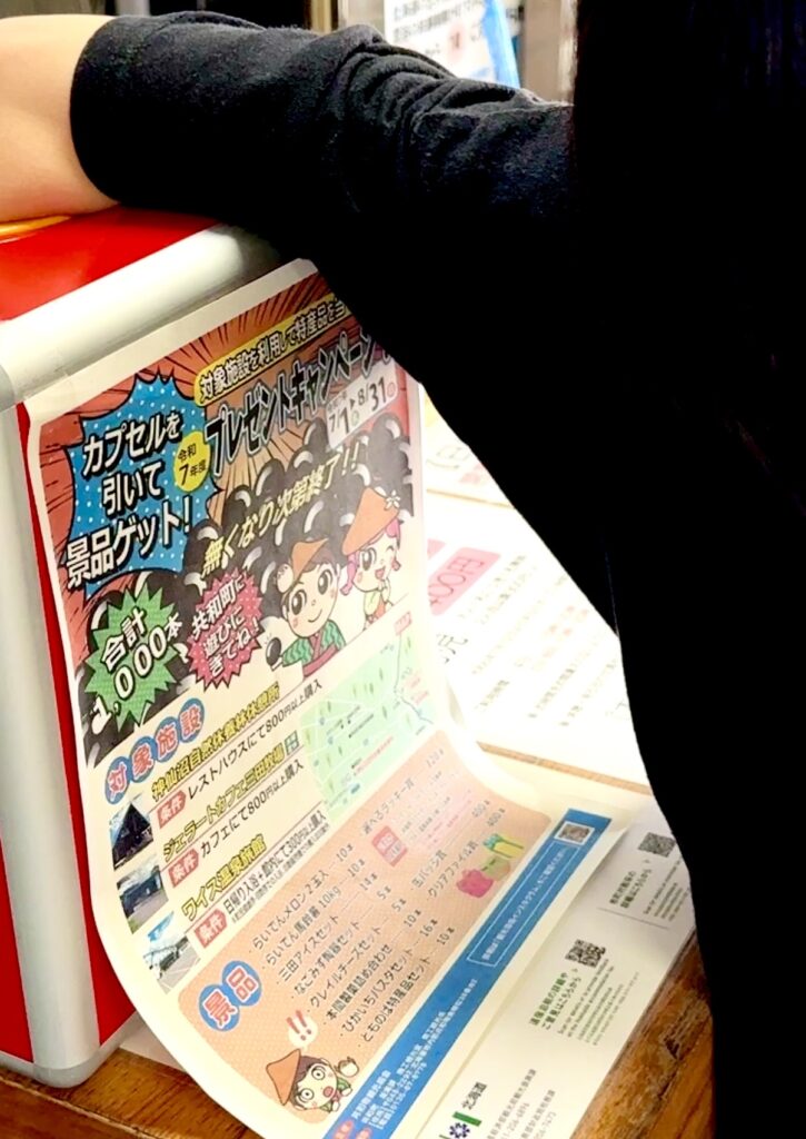 Elementary school-aged daughter drawing a prize capsule during the campaign at Waisu Onsen