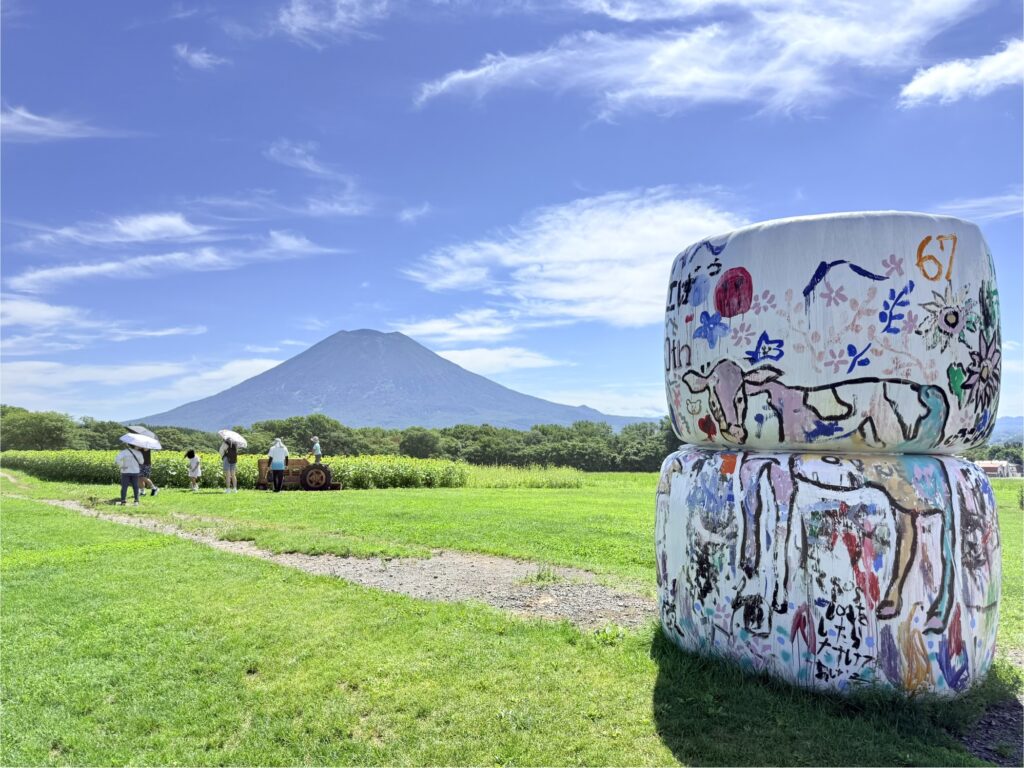 ニセコの高橋牧場牧草ロールと木のトラクターと羊蹄山