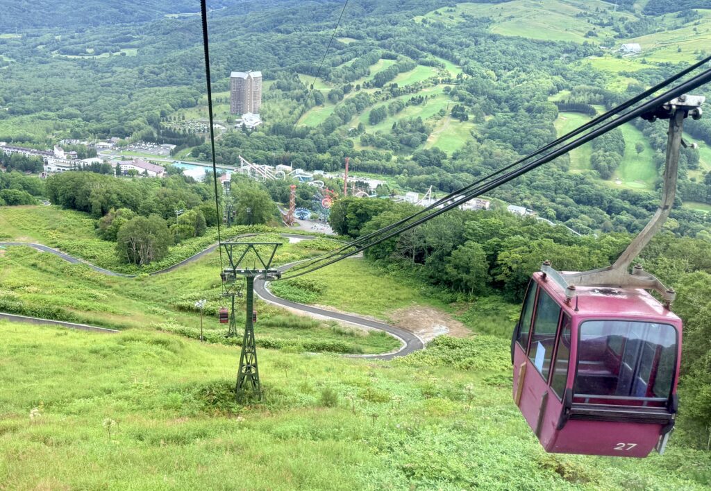 夏のルスツリゾートを走るピンクの羊蹄ゴンドラと緑の山