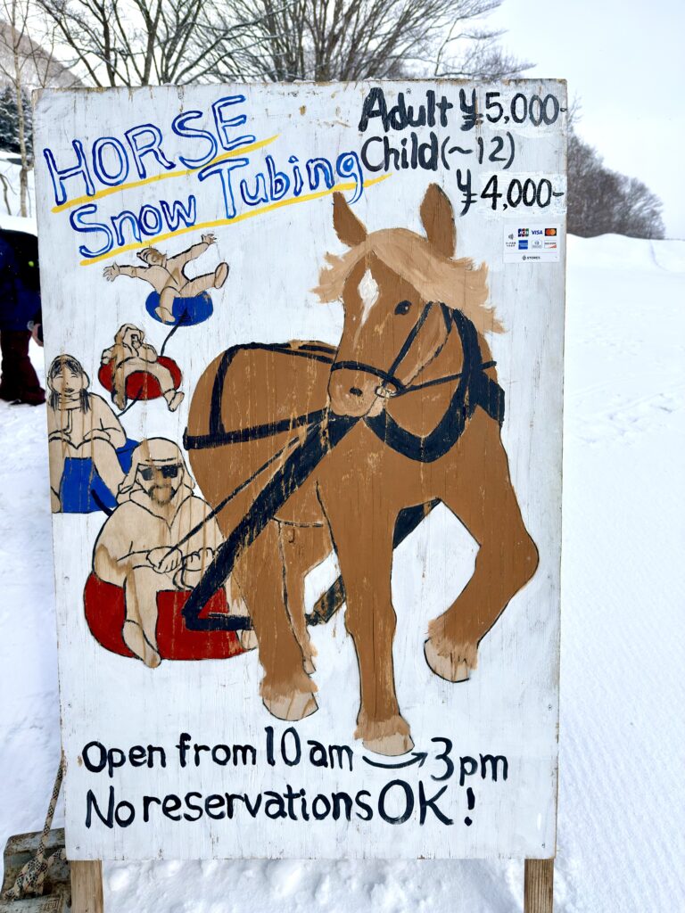 ニセコビレッジ前の馬のスノーラフティング体験看板