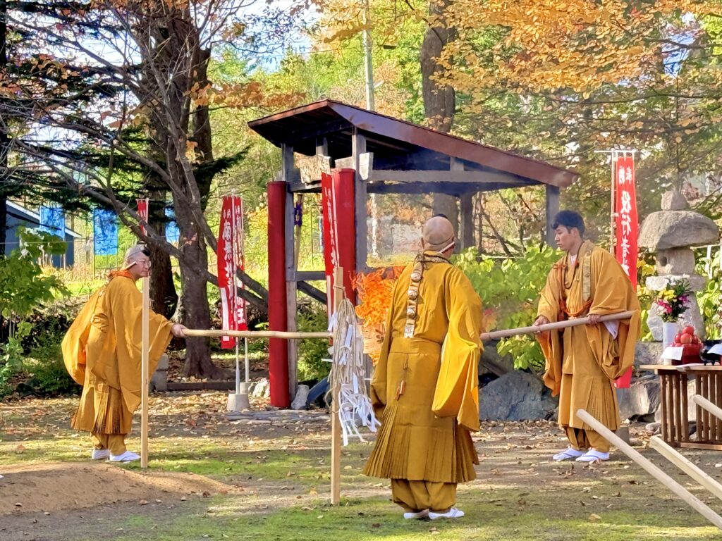 倶知安町の金毘羅寺で火渡りの儀を行う黄色い法衣の僧侶たちと燃え上がる炎