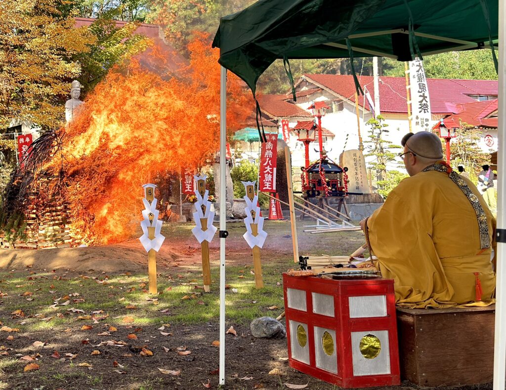 倶知安・金毘羅寺の火渡りの儀で紅葉を背景に大きく燃え上がる炎