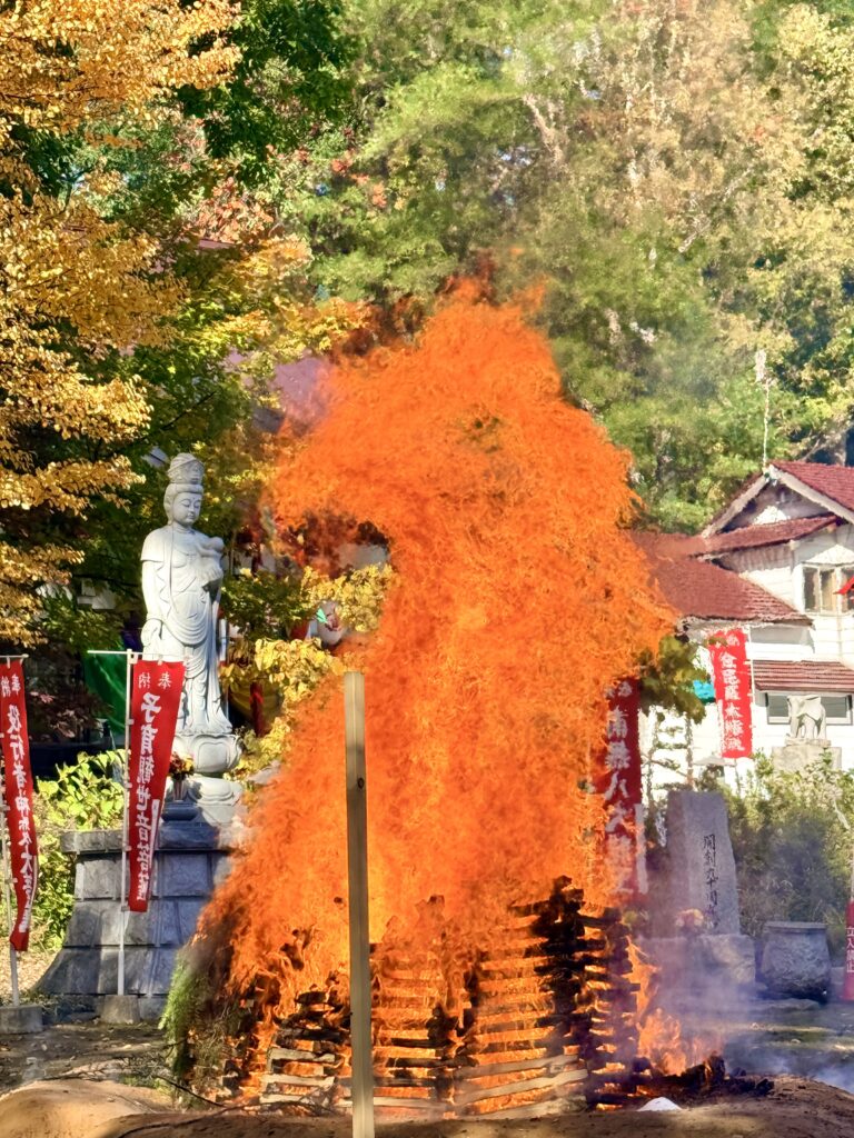金毘羅寺の火渡りで木組みから高く燃え上がる炎と境内の観音像
