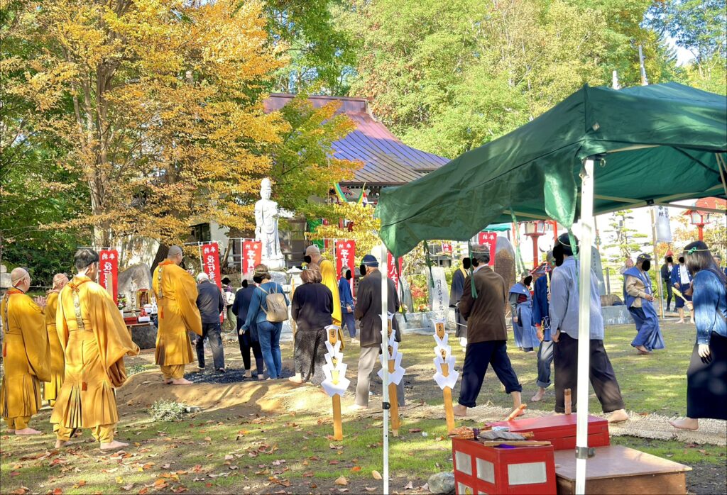 倶知安・金毘羅寺の火渡りの儀で黒くなった炭の上を裸足で歩く参拝者たち